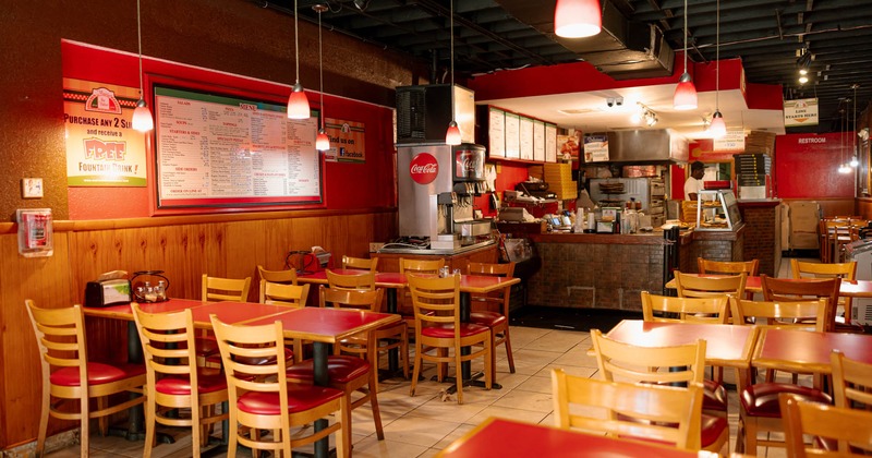 Interior, dining area, tables set up for six people, large menu board, soda fountain