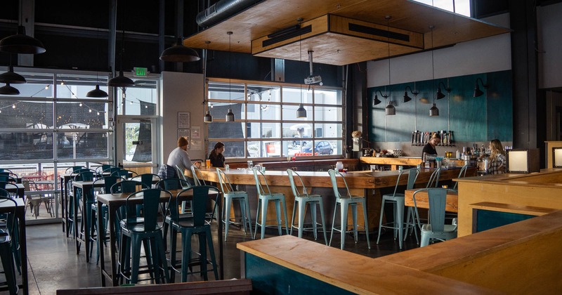 Interior, seating area, bar with thick wood slab as a counter top, bar stools, patio in the back