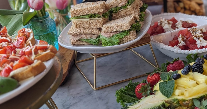 A buffet table filled with sandwiches, fresh fruit, and various other delicious foods