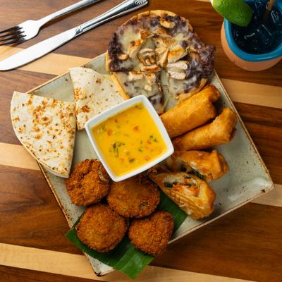 Appetizer sampler with fried bites, quesadilla, flatbread, and dipping sauce.