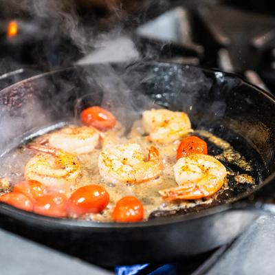 Sizzling shrimp and cherry tomatoes cooking in a cast iron skillet.