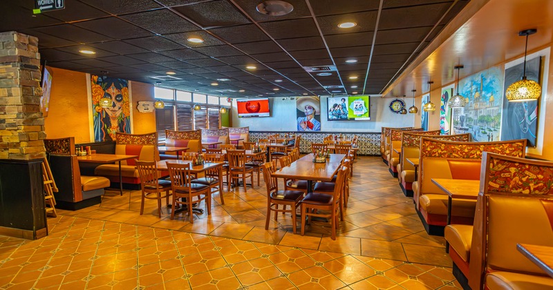 Interior of a restaurant with wooden tables, chairs, and booths, decorated with artwork