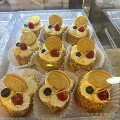 Cupcakes each topped with cream, cookie, and berries.