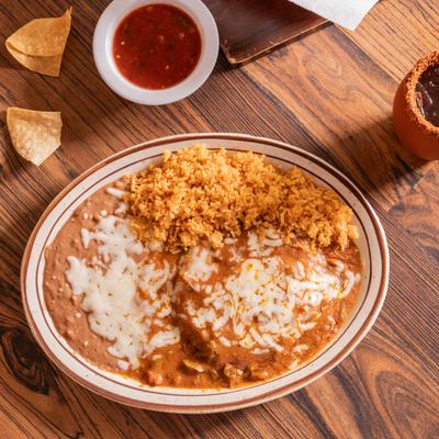Dish covered in sauce, and cheese, served with rice, and refried beans.
