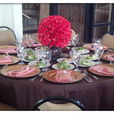 Vibrant pink roses center a sophisticated table set with gold-rimmed plates.