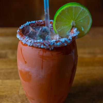 Cantarito cocktail served in a traditional clay cup, with salted rim and lime slice.