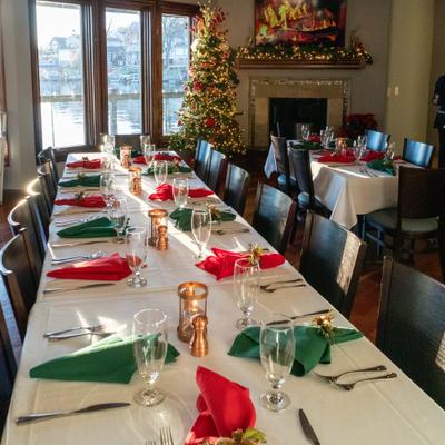 Festive dining room with a long table set for a holiday meal and a decorated Christmas tree.