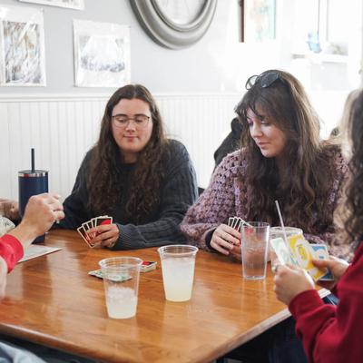 A group of friends playing cards at a table with drinks.