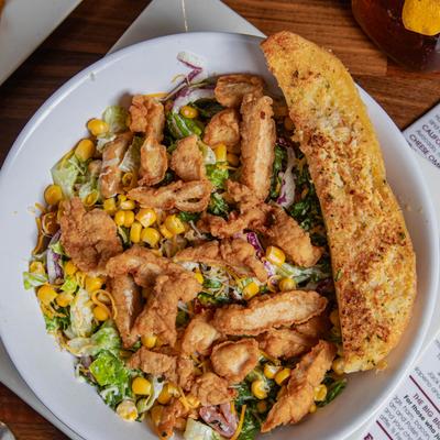 Fried chicken salad served with garlic bread, top view.
