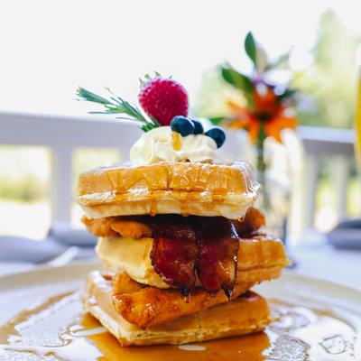 Waffle sandwich with fried chicken, bacon, whipped cream, and syrup.