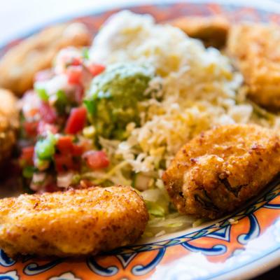Fried jalapeno poppers with pico de gallo, guacamole, shredded cheese, and lettuce.