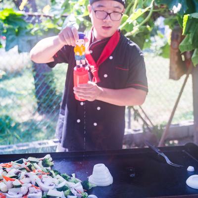 Chef seasoning vegetables on a grill.