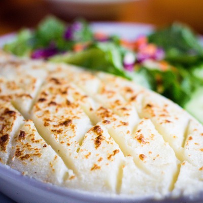 Crispy potatoes tops a dish of shepherd's pie served next to a salad of greens, carrots, cucumber and tomato