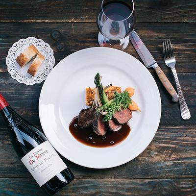 Rack of Lamb served with a glass of wine, top view.