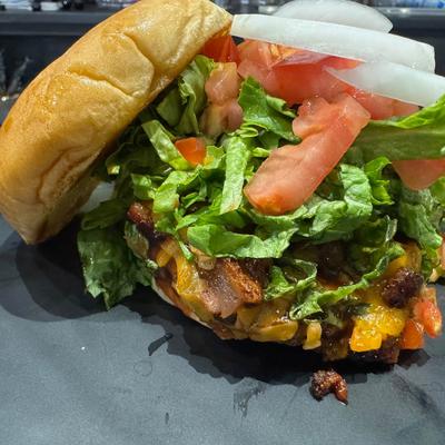 Bacon cheeseburger with shredded lettuce, diced tomatoes, and onions.