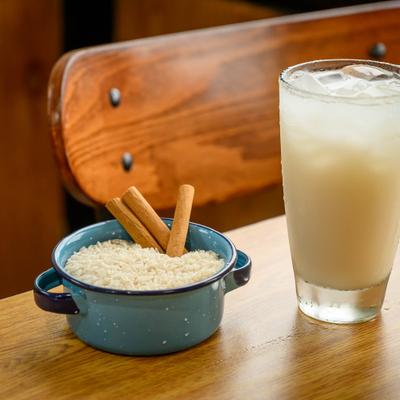 Horchata drink with a bowl of white rice and cinnamon sticks.