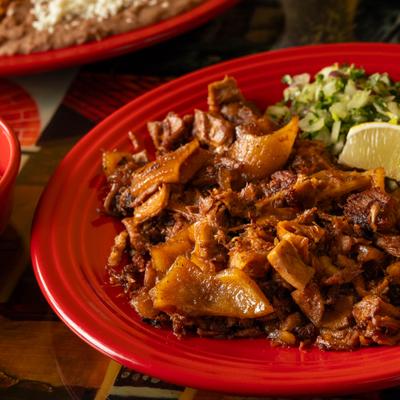 Chopped grilled meat on a red plate with onions.