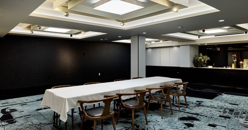 Inside, modern conference room with a rectangular table, wooden chairs, and a map-patterned carpet