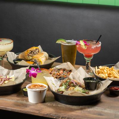 Mexican food and cocktails served on a wooden table.