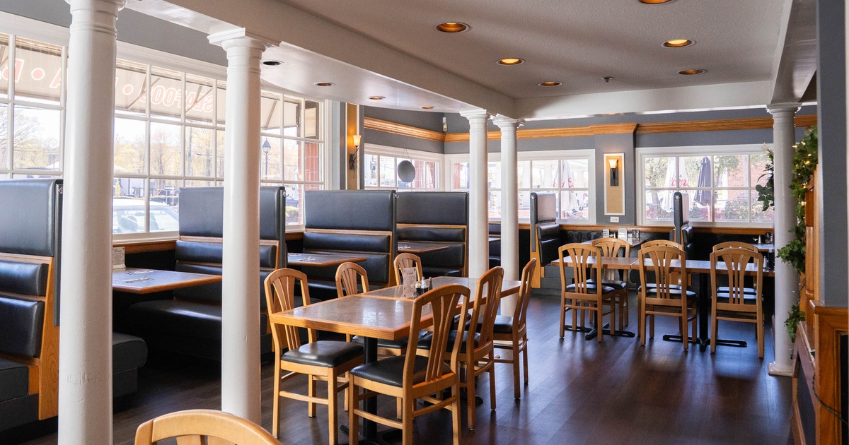 Interior of a restaurant with blue upholstered booths, wooden tables, and chairs
