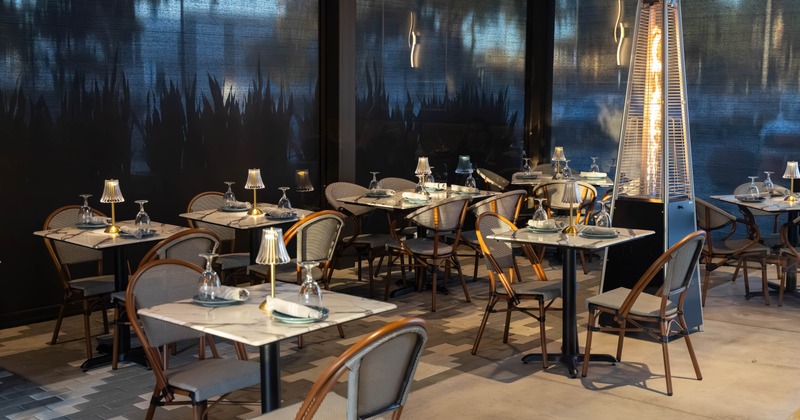 Exterior, patio, seating area, marble top tables for two and four, outdoor space heaters