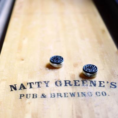 Shuffleboard table with Natty Greene’s logo and pucks.