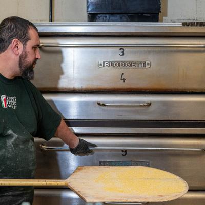 Pizza chef holding a pizza peel by the pizza ovens.