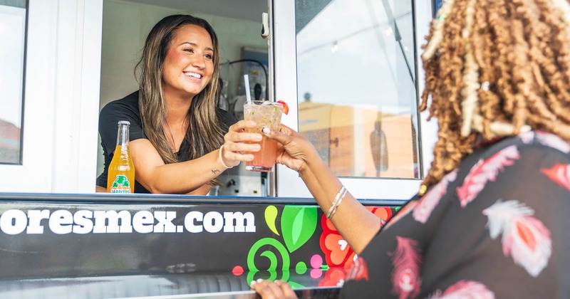 A food truck server hands a drink to a customer