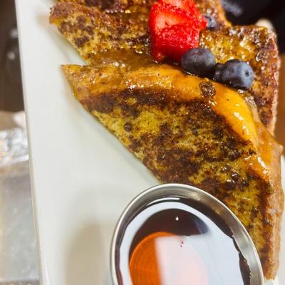 French toast topped with fresh berries and served with syrup on the side.