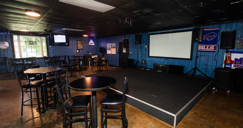 Interior with bar area, stage, projector screen, tables and chairs