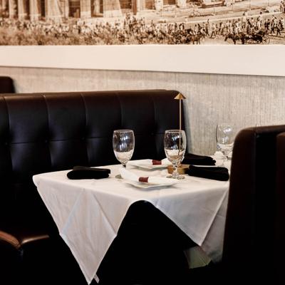Dining setup featuring plush black leather tufted booths and set tables.