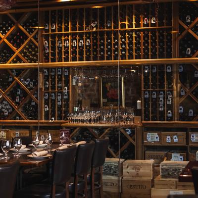 Elegant dining tables beside large wooden wine racks.
