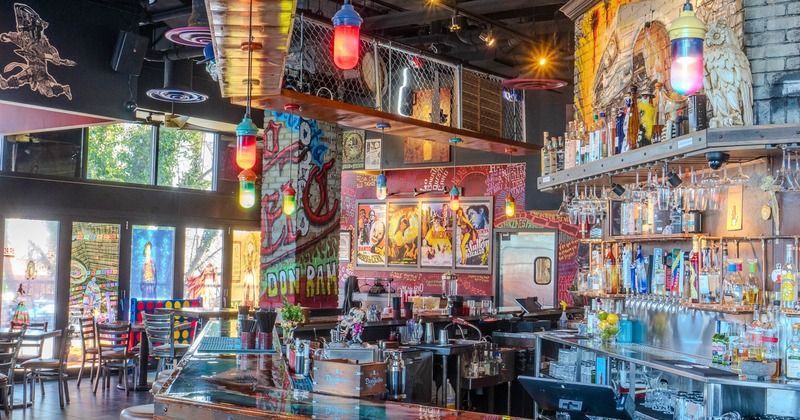 Vibrant interior with a bar, murals, colorful pendant lights, and painted windows