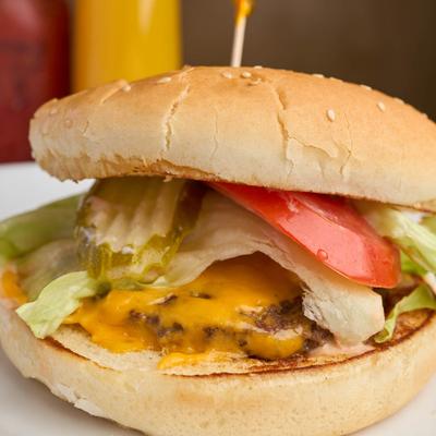 Cheeseburger with lettuce, pickle and tomato.