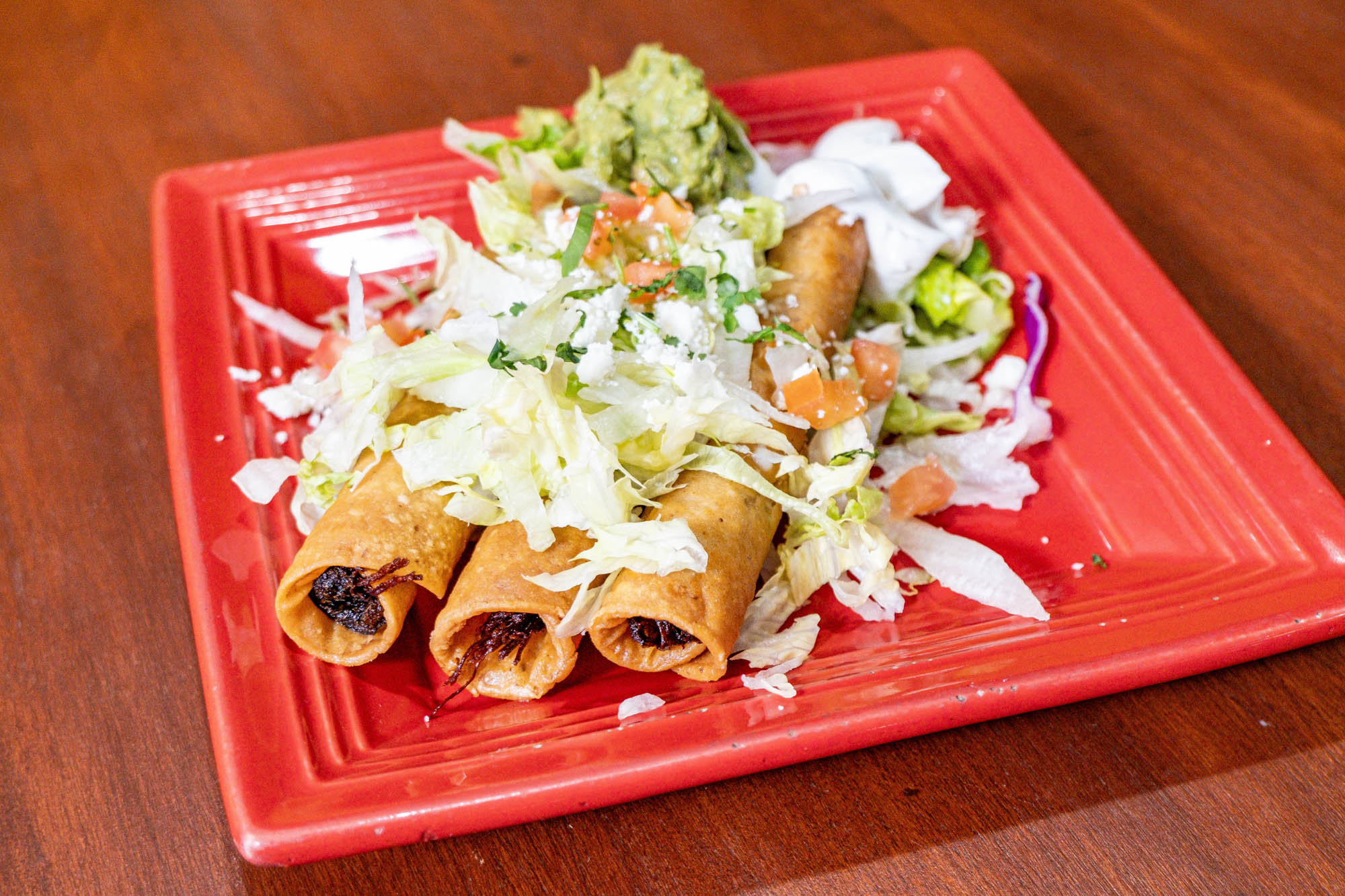 Taquitos, with lettuce, cheese, tomatoes, guacamole, and sour cream