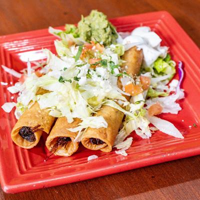 Taquitos, with lettuce, cheese, tomatoes, guacamole, and sour cream.