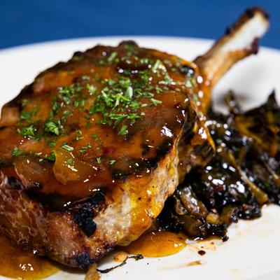 Grilled pork chop with mango chutney and braised field greens.