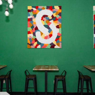 Cafe interior with a green wall, wooden tables, and colorful artwork.