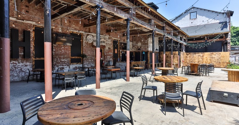 Exterior, seating area, cable spool tables with chairs, low hanging lanterns, concrete flooring