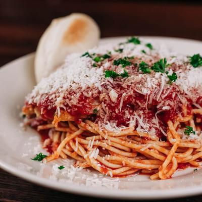 Chicken Parmesan with spaghetti, marinara sauce, herbs, and cheese.