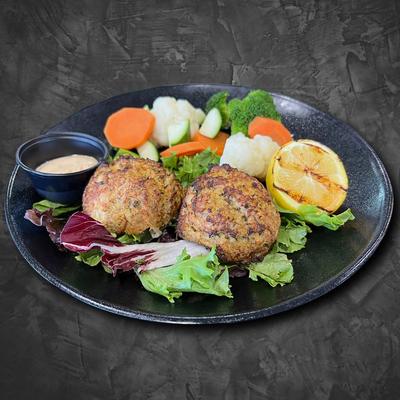 Crab cakes with veggies, lemon, and sauce.