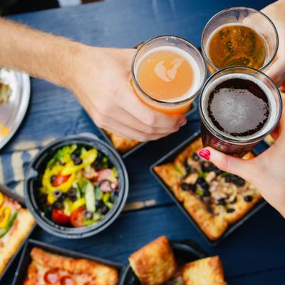 Cheers with beers over a table full of food.