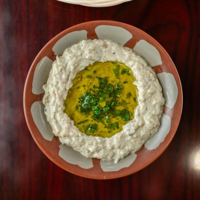 Baba ganoush topped with olive oil and parsley in a patterned bowl.