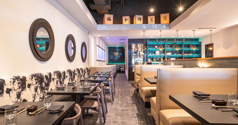 Interior, lined up set tables by a wall and restaurant booths, frontal view
