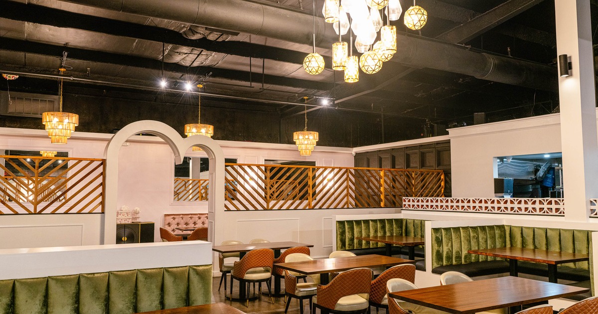 A modern interior - wooden tables, cushioned chairs, velvet banquettes, warm pendant lighting