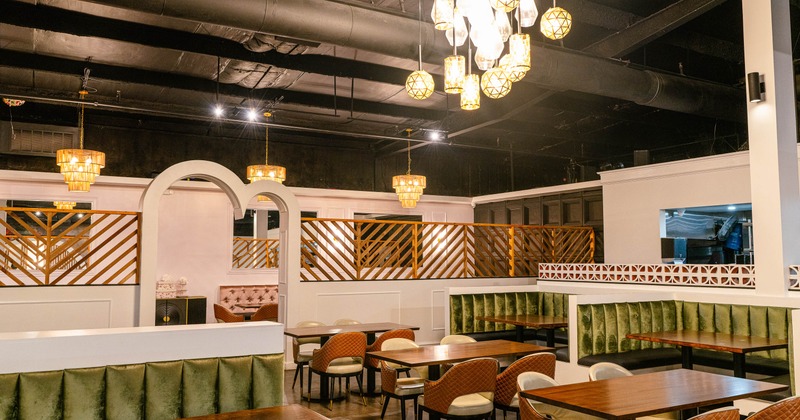 A modern interior - wooden tables, cushioned chairs, velvet banquettes, warm pendant lighting