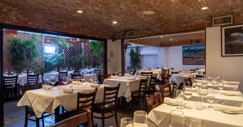 Interior, seating area, wooden top tables with wooden chairs, banquette bench in the back
