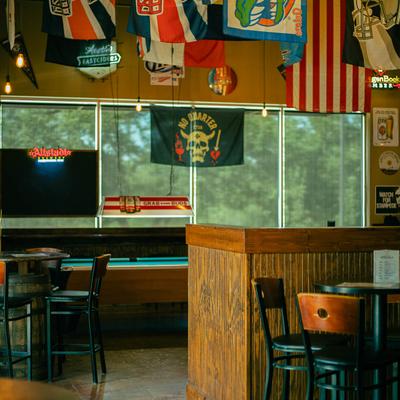 Sports bar interior with flags, tables, and a 'No Quarter' banner.