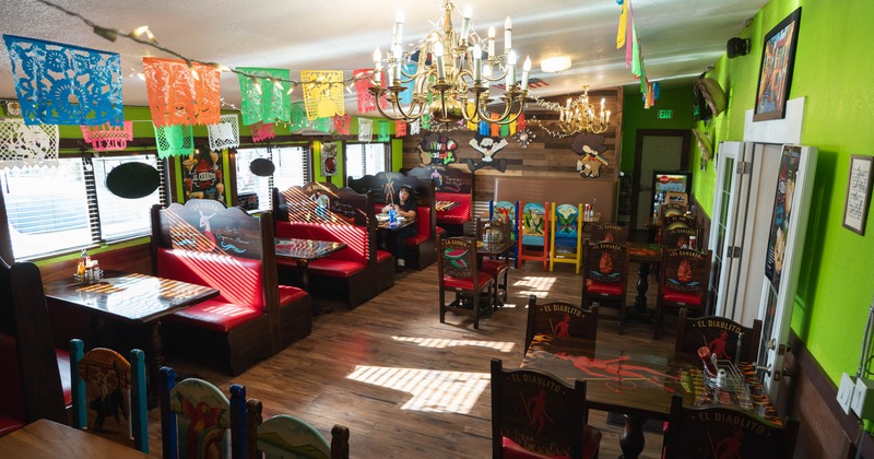 Interior of a Mexican restaurant with vibrant colors, papel picado banners, and red cushioned booths