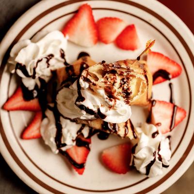 Pastry topped with cream, strawberries, and chocolate drizzle.